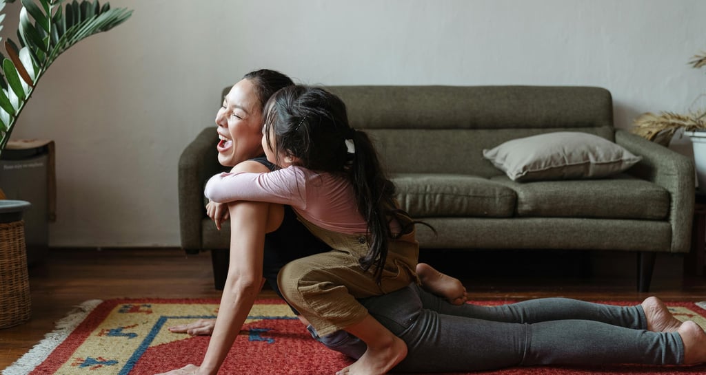 A mother in updog yoga pose. Her toddler is giving her a hug and kissing her.