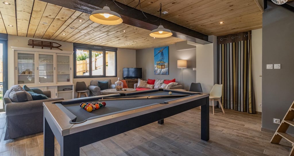 Salle commune du gîte l’Escale 1695 avec billard, coin salon et déco bois pour des vacances détente 