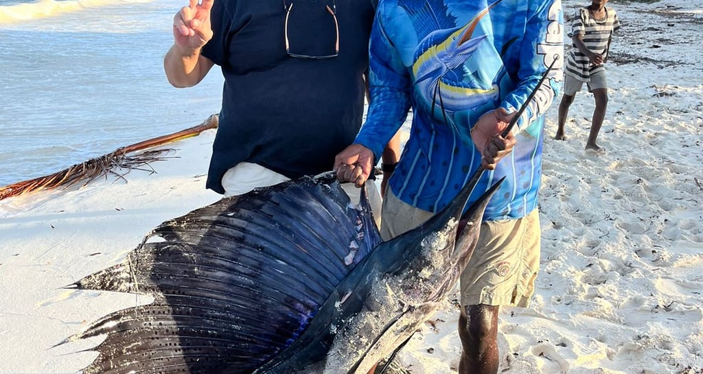 a man holding a fish on a beach