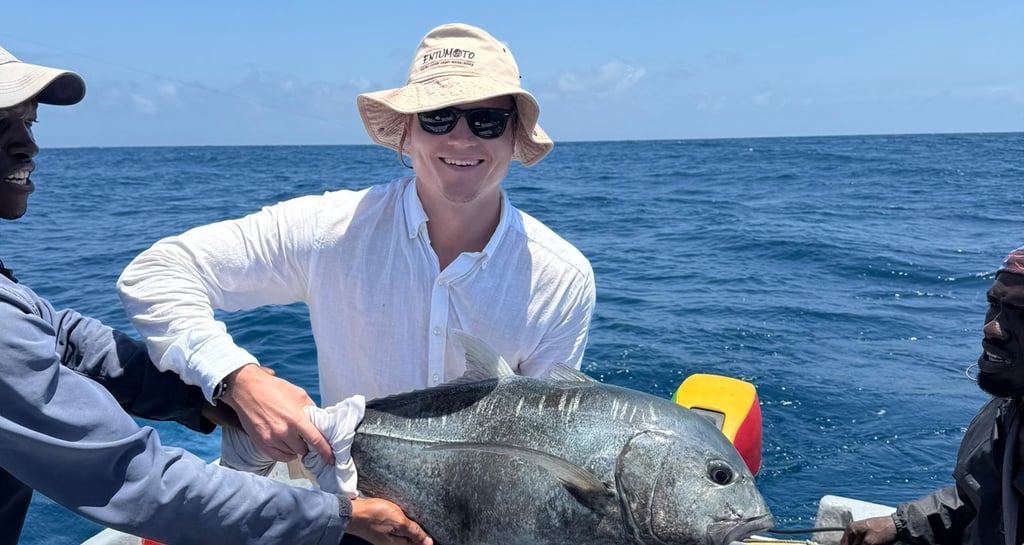 a man in a hat and sunglasses holding a fish