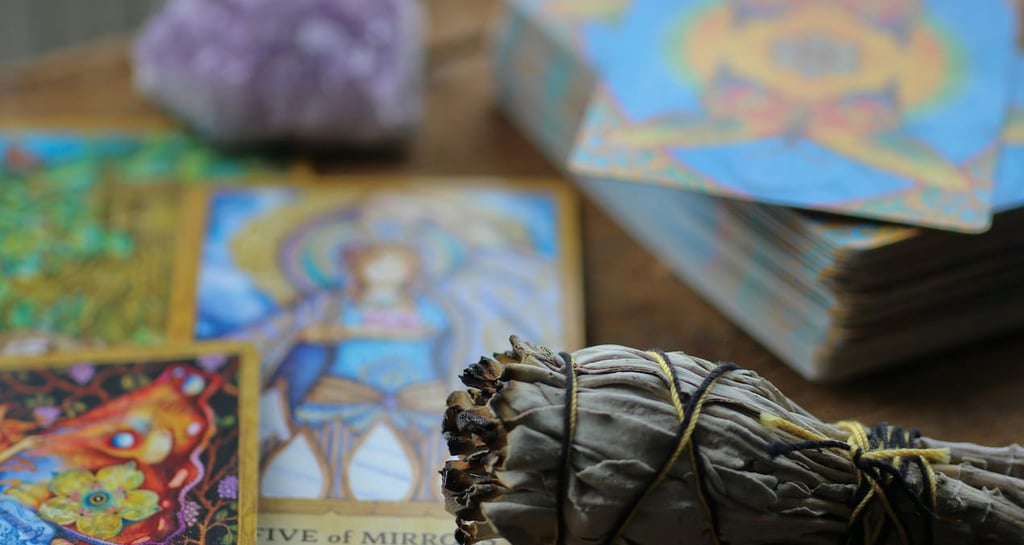 Sage bundle, amethyst crystal, and colorful tarot deck used in Amber’s energy readings.