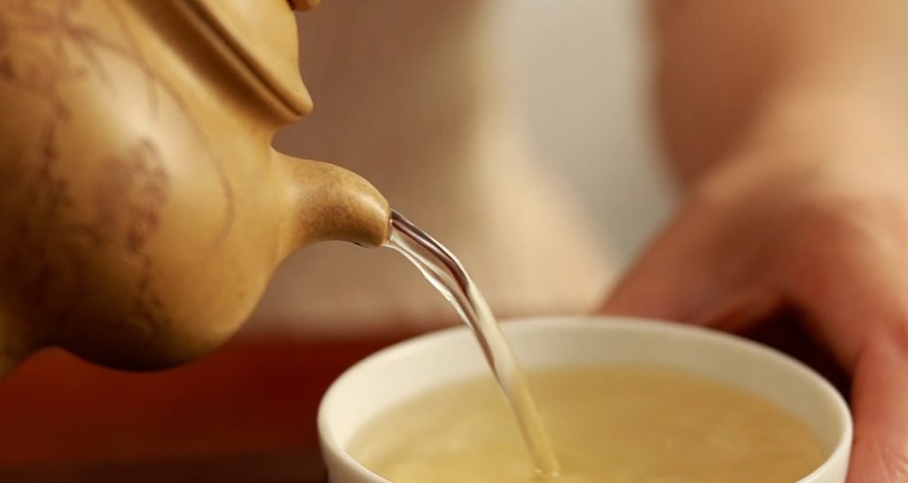 The teapot pouring tea into the teacup