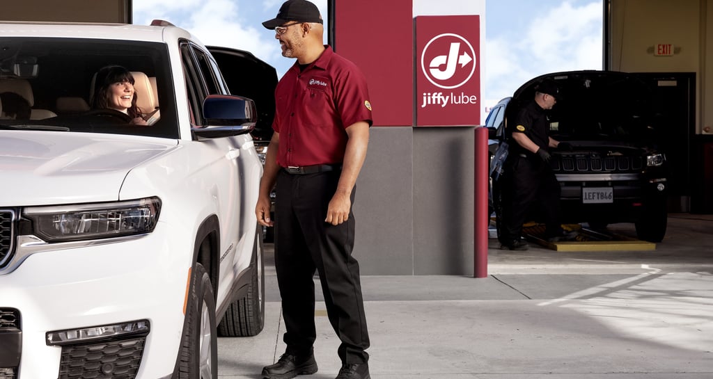 Employee greeting a customer in a white SUV.
