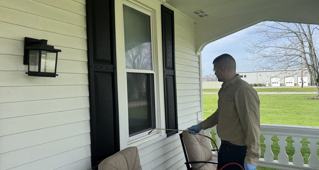 Pest control technician spraying around window