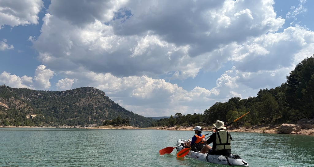 Piragua remando en el embalse de la Toba con un cielo nuboso precioso y montañas y vegetacion al fon