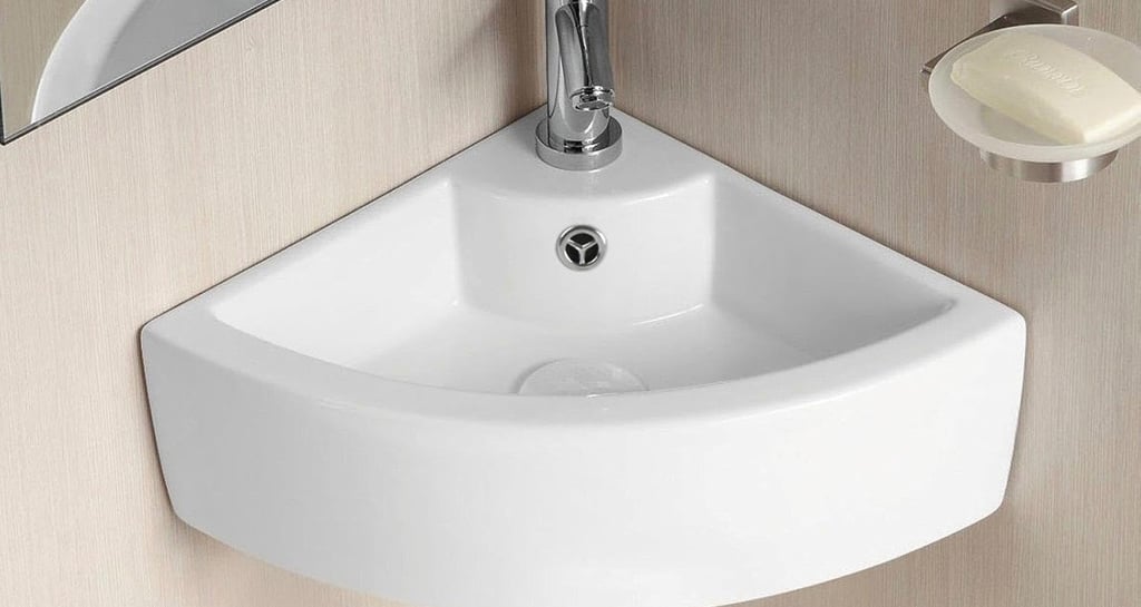 Small white ceramic corner wall-hung basin with chrome faucet and soap dish for compact bathrooms.