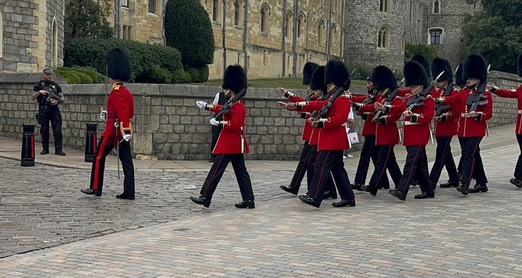 King's Guard in red tunics and bearskin hats marching at Windsor Castle.