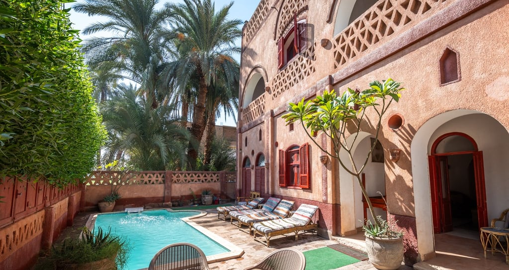 A courtyard featuring a private swimming pool, sun loungers, and tropical palm trees in Egypt.