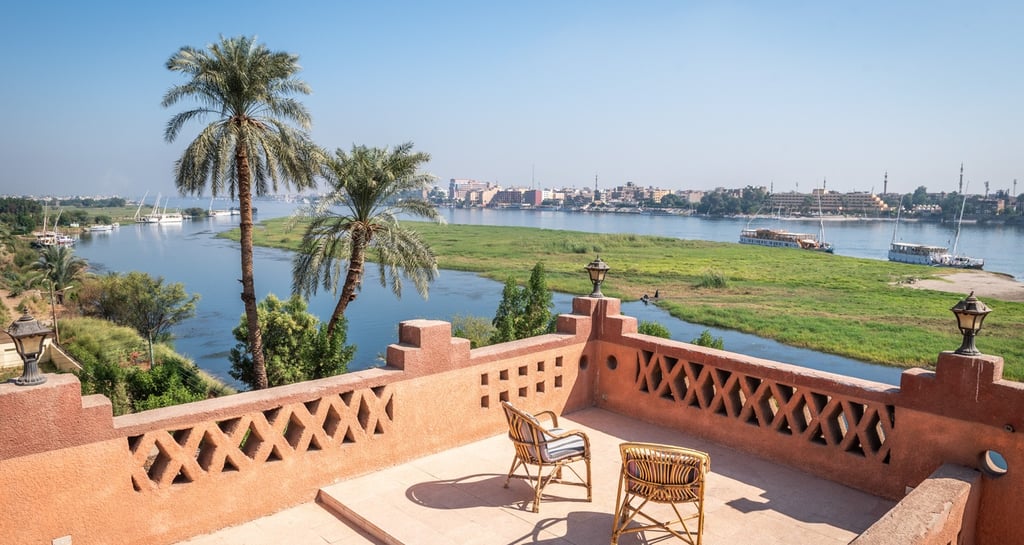 Luxury terrace balcony overlooking the Nile River in Egypt with palm trees and cruise ships.