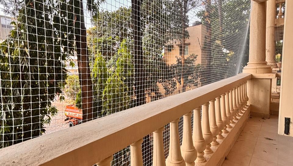 Evening shot of a balcony with safety nets softly illuminated by warm indoor lights.