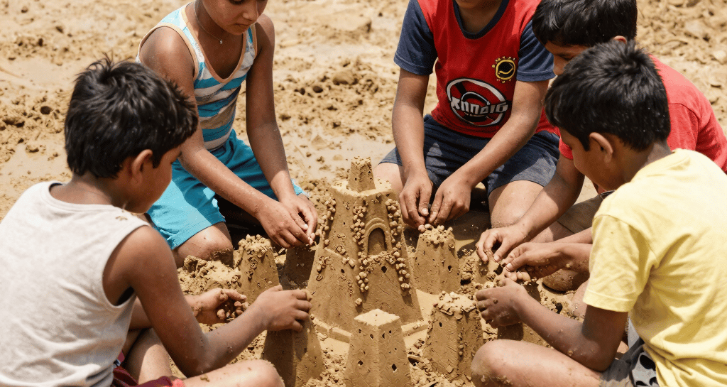 Children building sandcastles together in the sunny play area.