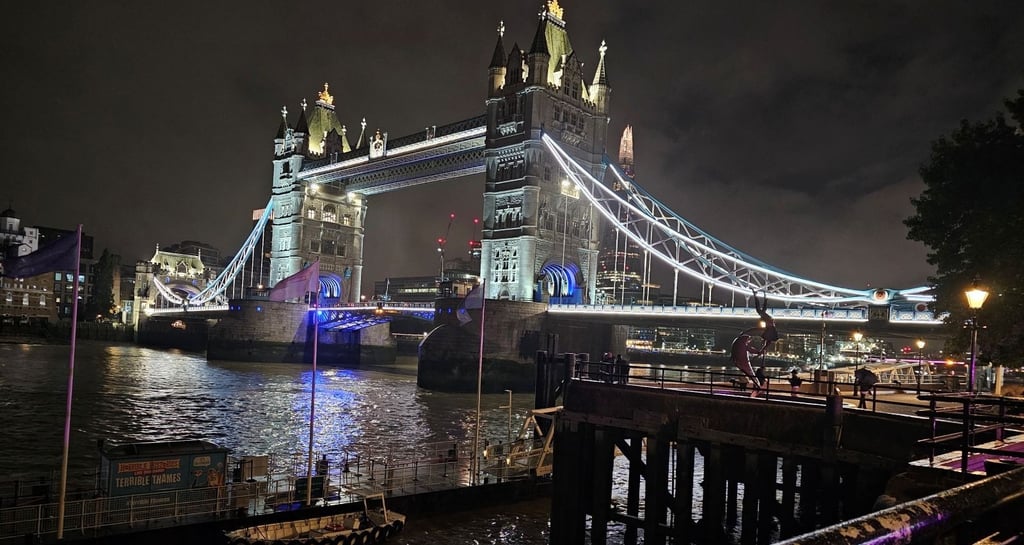 Night view of the illuminated Tower Bridge over River Thames in London with city lights.