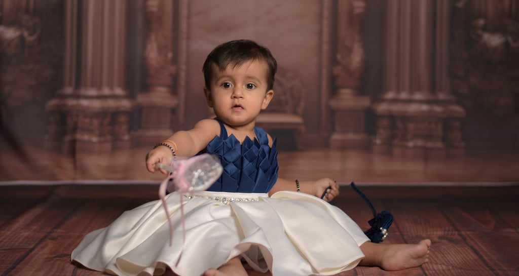 Baby girl in satin party dress sitting for a professional studio photoshoot. Wonderpose photography
