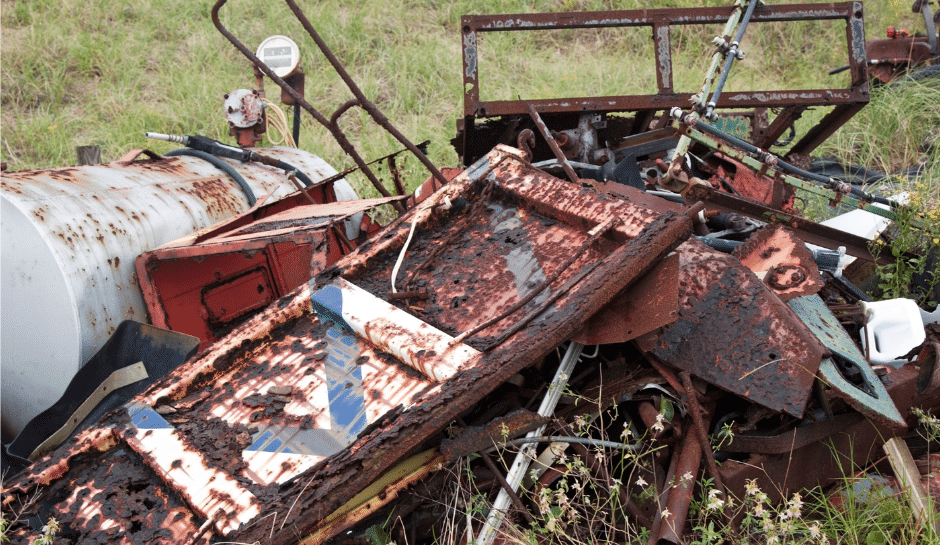 A large pile of junk including old metal doors, tanks, old fencing, old broken lawnmowers, and more.