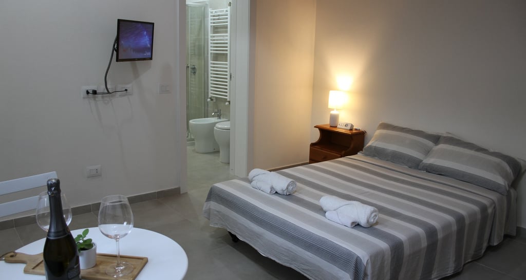 Lodgings in Sardinia a bedroom with a bed and a table with wine glasses