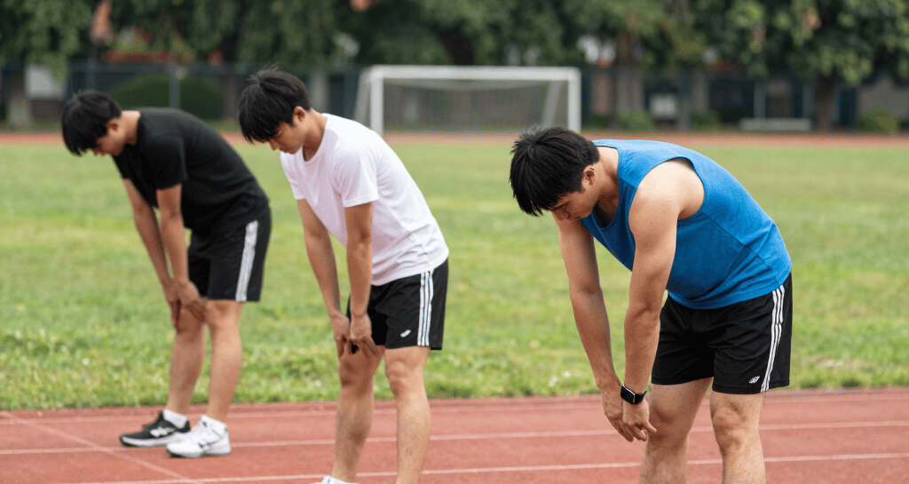 A casual group of men sharing a post-workout stretch session in a park.