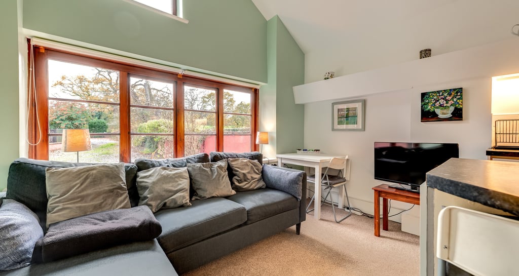 Modern living room featuring a grey sectional sofa, large windows, and a small dining area.