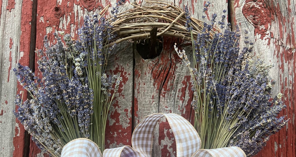 a wreath made of dried lavender flowers on a red barn door