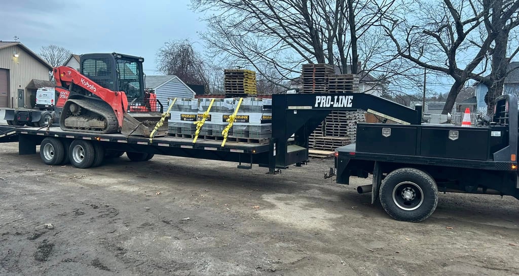 A red Kubota compact track loader and construction supplies on a black Pro-Line gooseneck trailer.
