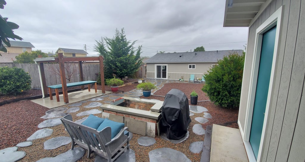 Custom backyard shed with teal door, custom decorative concrete stepping stones, and reclaimed wood outdoor table.