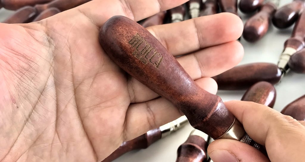 Manos sosteniendo una pieza de madera grabada con laser 