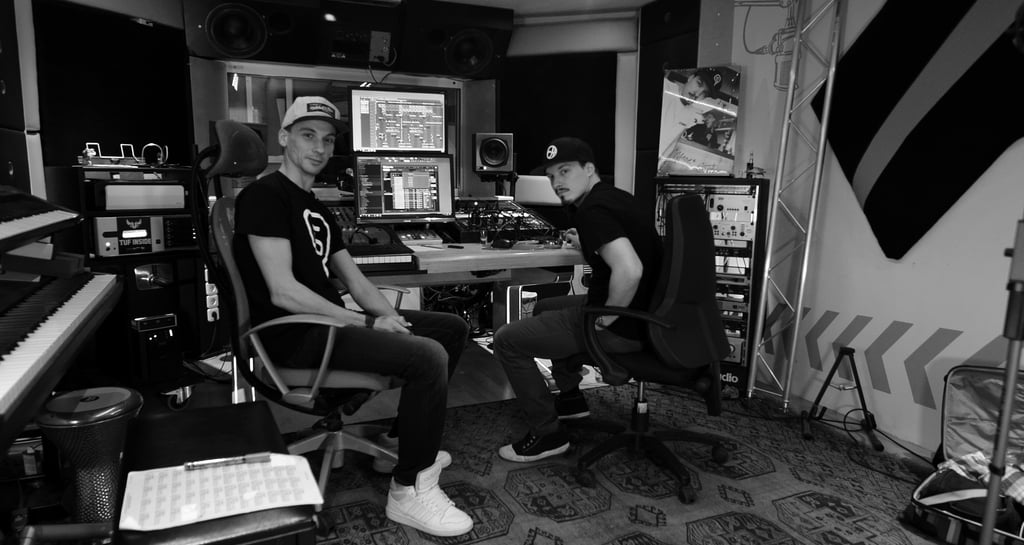 two men sitting in a recording studio producing hip-hop