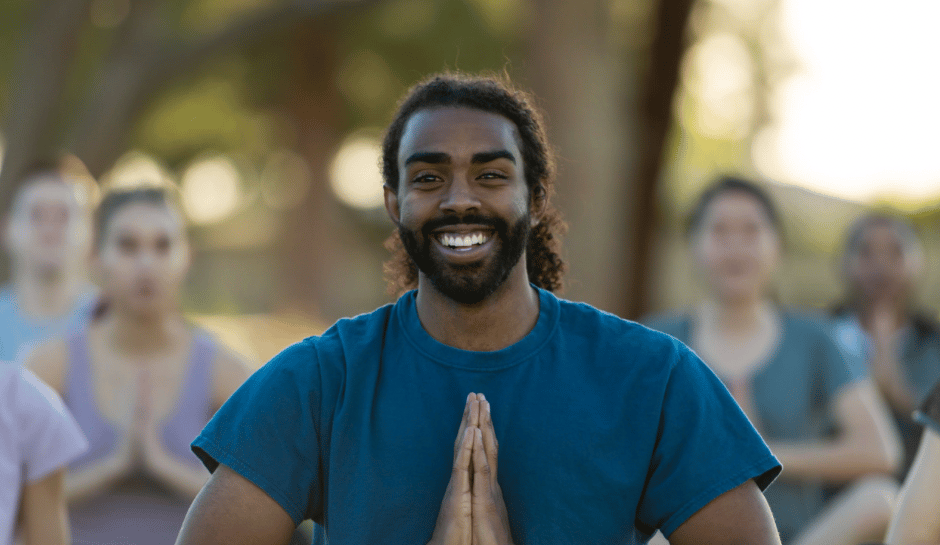 a man in a blue shirt sitting in a pose of gratitude