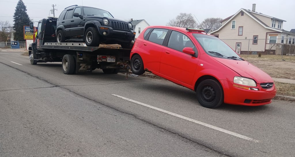 Flatbed tow truck removing a junk car in Detroit