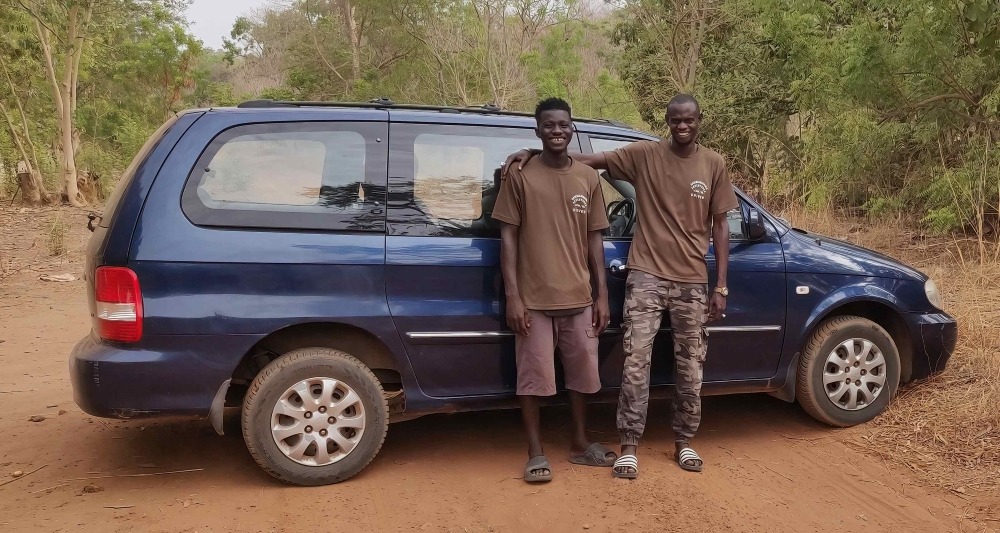 Twee gidsen van Birding Adventures Gambia & Senegal naast een blauwe minibus.