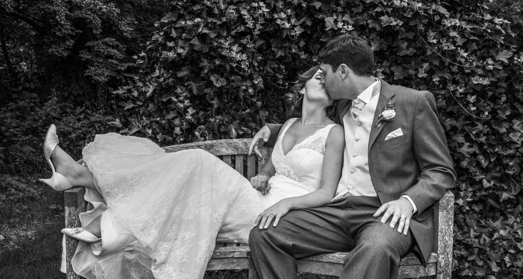 Husband kisses wife on a wooden bench