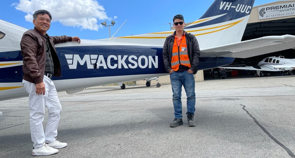 a man standing next to a plane with a man in a vest