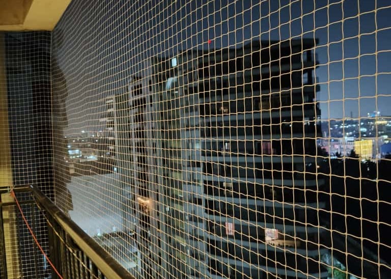 Close-up of durable anti-pigeon netting installed on a balcony in Koyambedu.