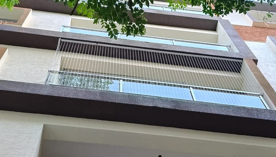 Close-up of a sleek invisible grill seamlessly blending with a balcony railing in Alwarpet.