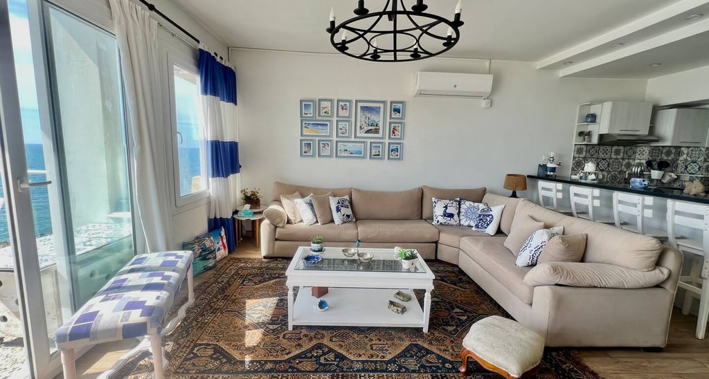 Modern seaside living room with a beige sectional sofa, vintage Persian rug, and ocean view balcony.