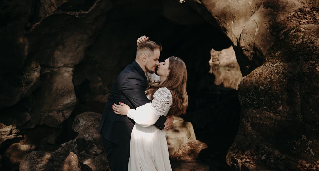a man and woman standing in front of a cave wedding photo