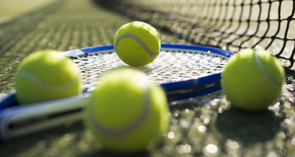 Raqueta y pelotas de tenis en cancha de tenis