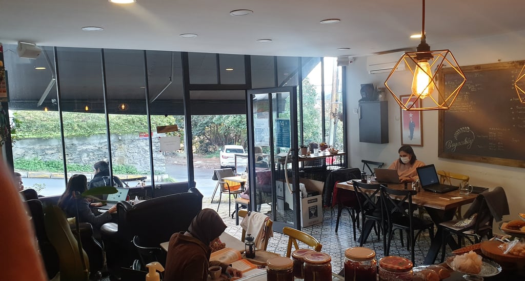 masalarda çalışan insanların bir şeyler yiyip içtiği bir kafe