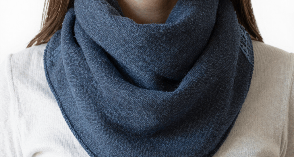Close-up of a colorful handmade snood scarf draped elegantly on a rustic wooden chair.