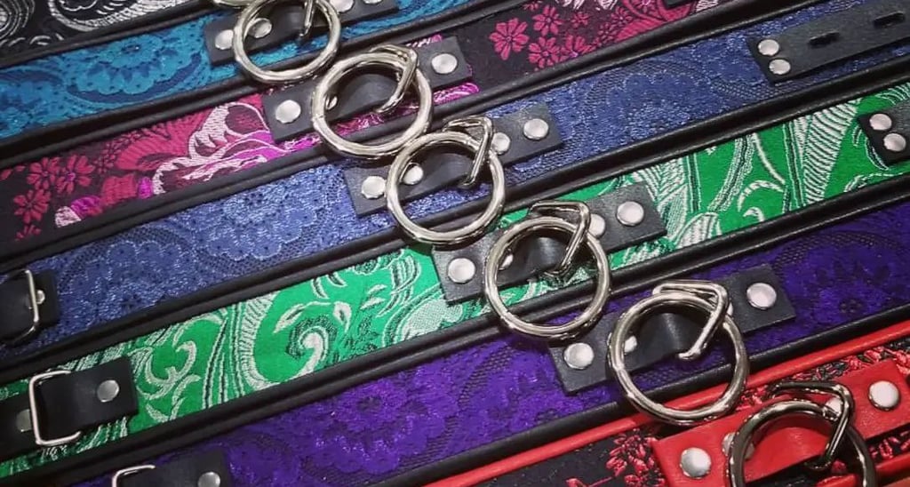 Handmade leather collars with metal O-rings in various floral patterns and colors.
