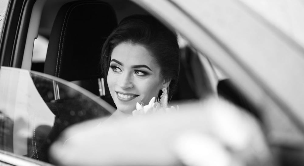 Vestuvių fotosesija. Jaunoji automobilyje su gėlių puokšte