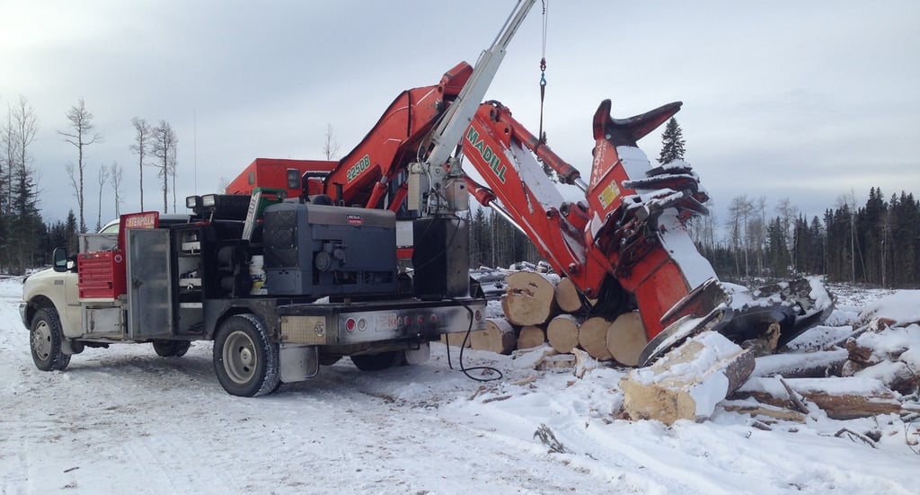 Service truck with picker working on feller buncher