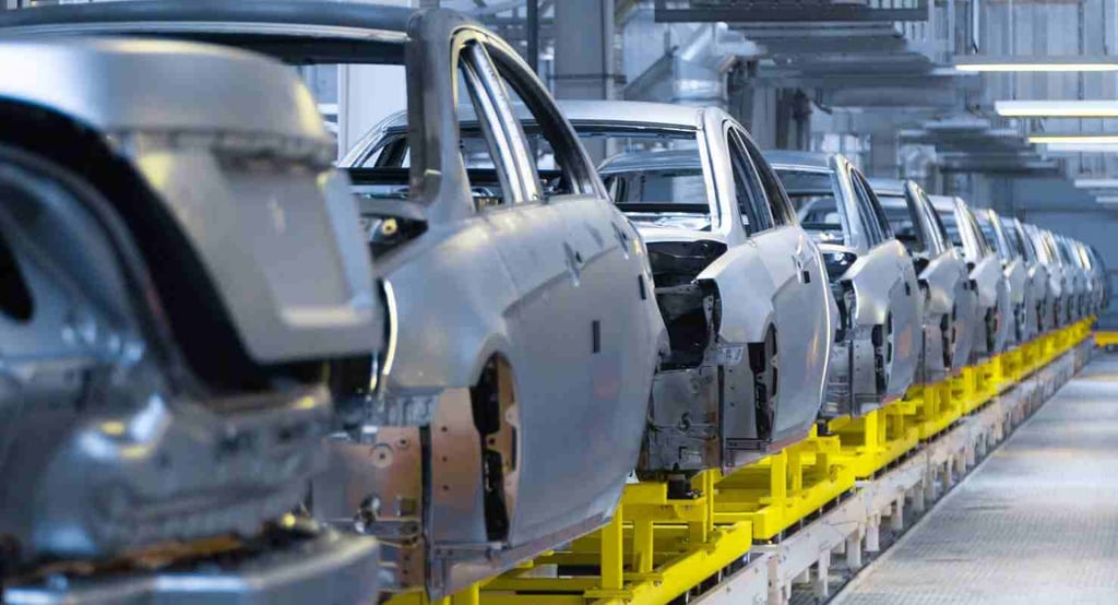 Automotive assembly line showing car body frames on a conveyor belt in a modern manufacturing plant.