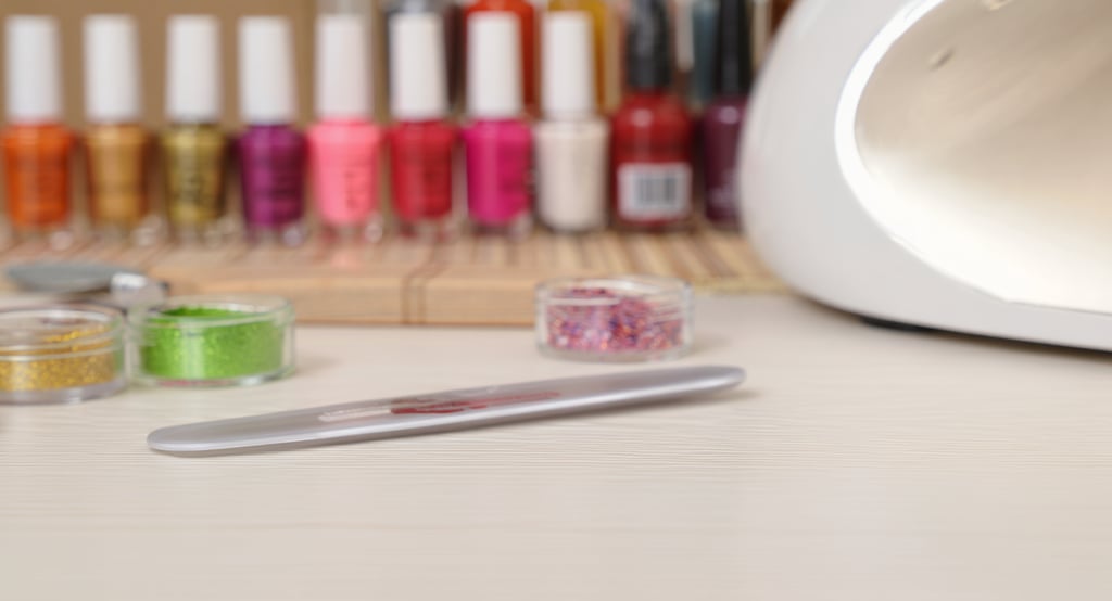 lime, brillantini lampade e smalti appoggiati su un tavolo di legno bianco