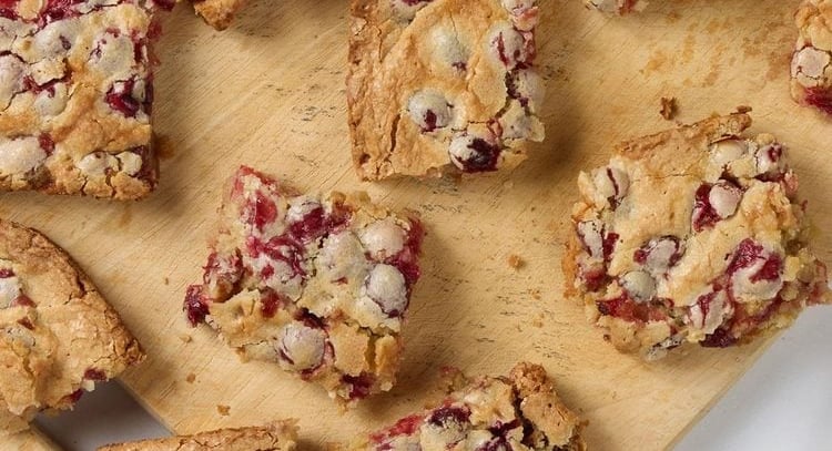 squares of cut cranberry cake on a wood board