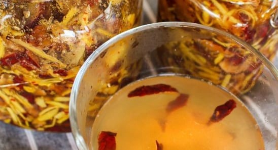Glass of tea with jujube and honey, jars of fruit behind
