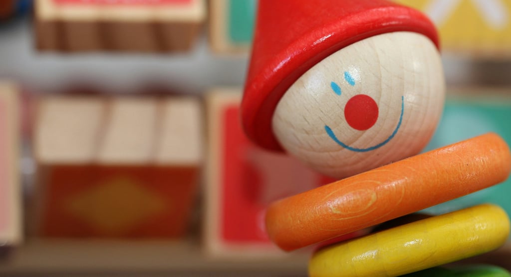 Close-up of colorful wooden clown toy with alphabet blocks, symbolizing childhood and playful learni