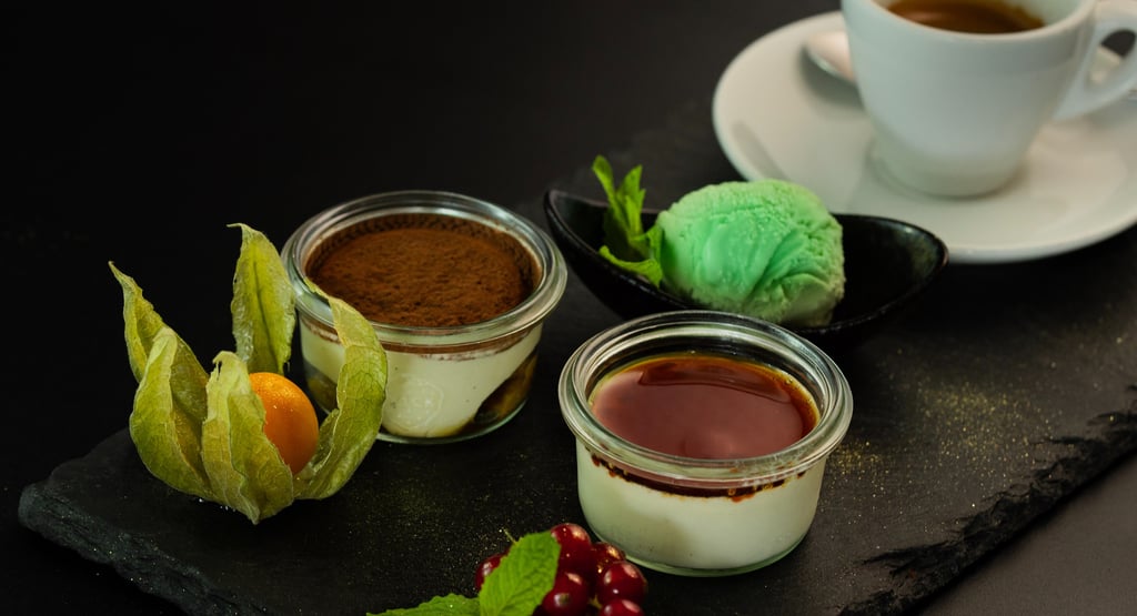 Tiramisu- und Panna-Cotta-Desserts in Gläsern serviert mit Minzeis und Espresso.