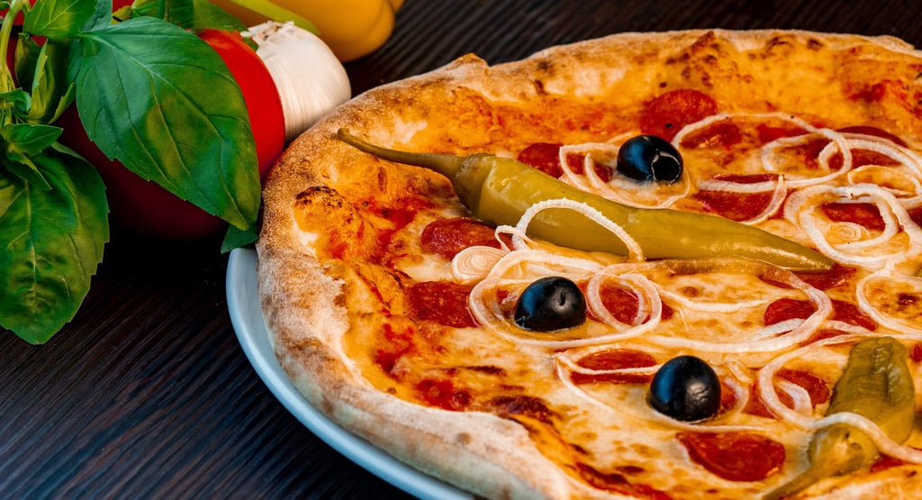 Steinofen-Peperoni-Pizza mit schwarzen Oliven, Zwiebeln und scharfen grünen Paprika auf einem rustik