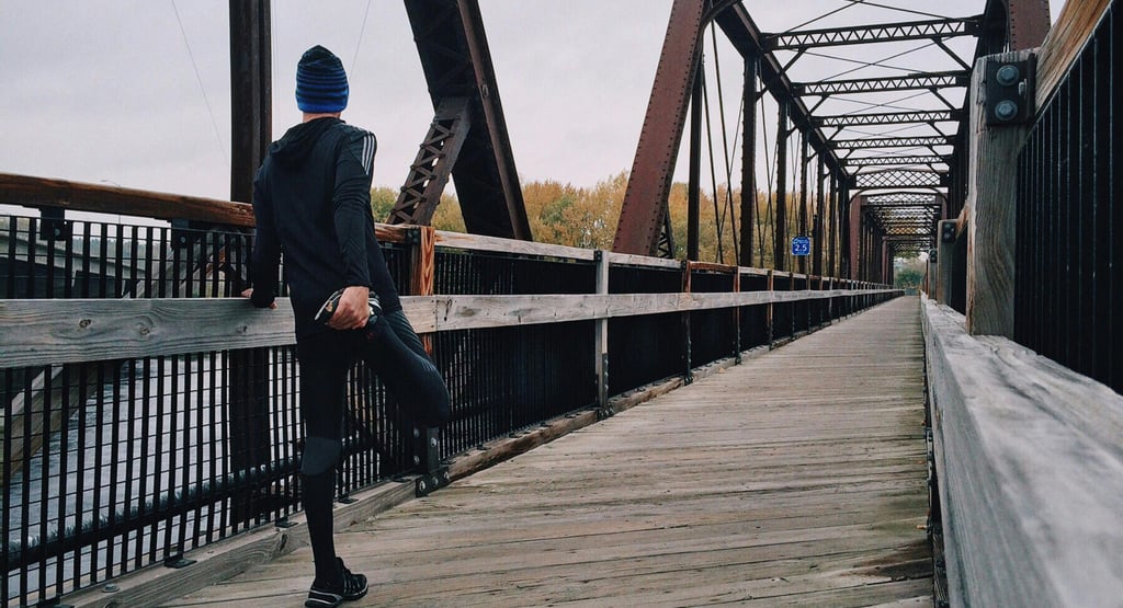 a man in a blue hat and a blue jacket is standing on a bridge