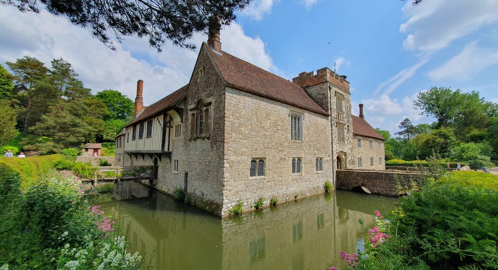 View of the house at Ightham Mote, surrounded by water.